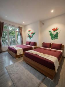 two beds in a room with paintings on the wall at Big Home Dalat in Da Lat
