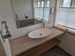 ein Badezimmer mit einem weißen Waschbecken und einem Spiegel in der Unterkunft Strandhuset in Agger