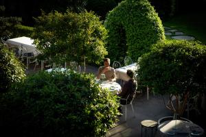 two people sitting at a table in a garden at Hotel Magdalener Hof in Bolzano