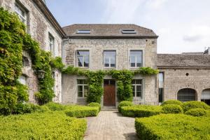 a stone house with a door and bushes at Entre Pierres et Rivière - 2 Gites avec wellness privatifs in Hotton