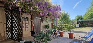 a patio with tables and chairs and purple flowers at Il Mulino B&B in Rivara