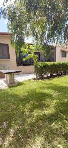 a park bench sitting in the grass in front of a building at Marathon Βeach Ηouse in Panayía Mesosporítissa