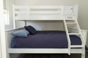 a bunk bed in a room with a pillow and a ladder at Bay Motel Safety Beach in Safety Beach