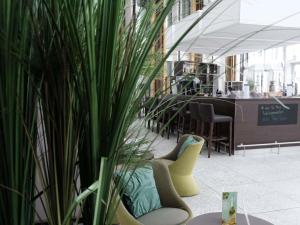 a room with chairs and a potted plant in a building at Webers Hotel im Ruhrturm Essen by Accor in Essen