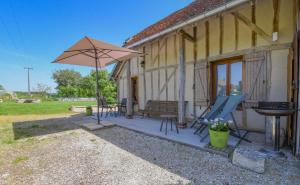 a patio with an umbrella and chairs and a grill at La louvière in Jeugny