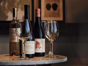 three bottles of wine sitting on a table with glasses at Nirema Hotel & Spa Samos - MGallery Collection in Samos