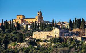 a large building on top of a hill with trees at Orto dei Frati in Sortino
