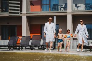 a family walking on a sidewalk next to a building at Hotel Akvamarín in Bešeňová +49 photos