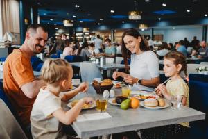 a family eating food at a table in a restaurant at Hotel Akvamarín in Bešeňová