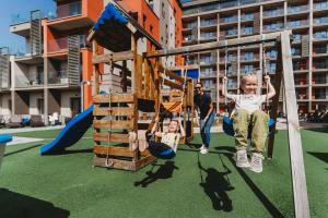 two children playing on a swing set in a playground at Hotel Akvamarín in Bešeňová