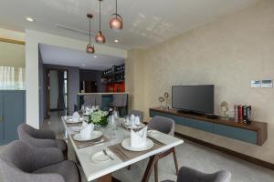 a dining room with a table and chairs and a television at DIC Star Villas Vinh Phuc in Vị Trù