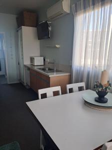 a kitchen with a white table and chairs and a sink at Headlands Hotel in Opunake