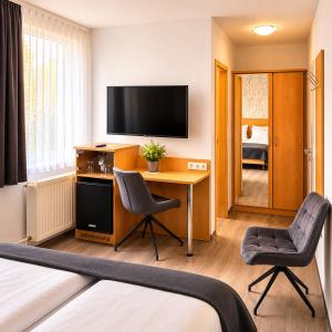 a hotel room with a desk and a television at Hotel am Kurpark in Bad Lauterberg