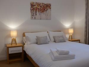 a bedroom with a white bed with two lamps at St Raphael House, City Centre Charming Apartments in Basingstoke