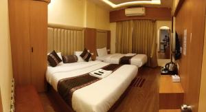 a hotel room with two beds and a television at Hotel Rajwada Nagpur in Nagpur