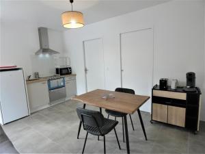 a kitchen with a wooden table and chairs in it at Le clémens in Herm