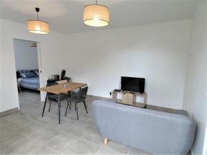 a living room with a couch and a table with a tv at Le clémens in Herm