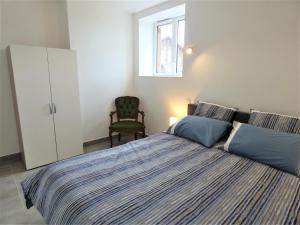 a bedroom with a bed with blue pillows and a chair at Le clémens in Herm