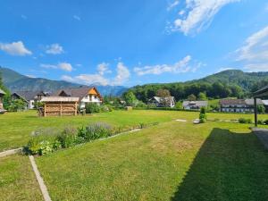 a large yard with a house and mountains in the background at Bohinjski kot in Bohinj
