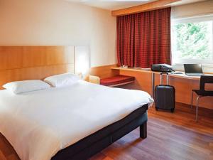 a bedroom with a bed and a desk with a laptop at ibis Belfort Danjoutin in Belfort +83 photos
