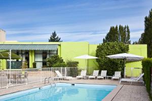a pool with chairs and umbrellas next to a building at ibis Styles Chalon sur Saône in Chalon-sur-Saône