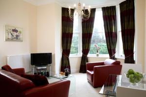 a living room with a couch and chairs and a tv at Sherborne House, City Centre Victorian Apartments in Basingstoke