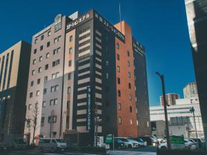 a tall building with cars parked in a parking lot at Hamamatsu Station Hotel in Hamamatsu