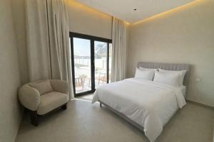 a bedroom with a bed and a chair and a window at Etlaala Chalet in Ibri