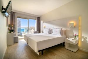 a bedroom with a large white bed and a large window at Helios Mallorca Hotel & Apartments in Can Pastilla