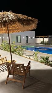 a chair and an umbrella next to a swimming pool at Etlaala Chalet in Ibri