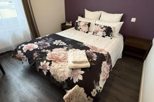 a bedroom with a bed with a black and pink floral blanket at Logis hôtel restaurant Auberge de la Cloche in Le Theil-sur-Huisne +15 photos