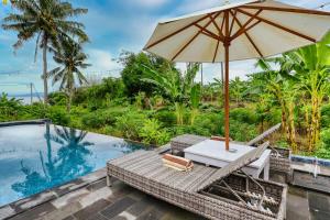 an umbrella and chairs next to a swimming pool at Bunut Bungalow in Nusa Penida