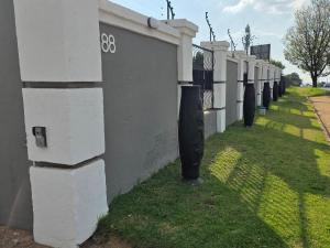 a row of white fences next to a grass yard at Phola Lodge OR Tambo in Kempton Park +3 photos