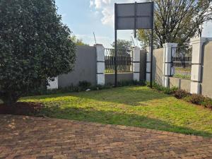 a fence with a sign in front of a yard at Phola Lodge OR Tambo in Kempton Park