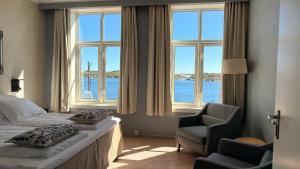 a bedroom with a bed and a chair and windows at Risør Hotel in Risør +72 photos