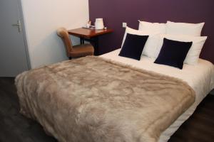 a bedroom with a large bed with a chair and a table at Logis hôtel restaurant Auberge de la Cloche in Le Theil-sur-Huisne