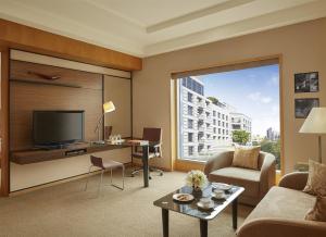 a living room with a tv and a large window at Grand Hyatt Mumbai Hotel and Residences in Mumbai