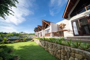 a house with a stone retaining wall and a yard at Nayandra Uluwatu in Uluwatu