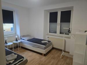 a small bedroom with a bed and two windows at Monteur-Apartment Kusel City in Kusel