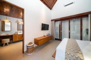 a bedroom with a large bed and a bathroom at Nayandra Uluwatu in Uluwatu