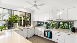 a kitchen with white cabinets and a ceiling fan at Wave Whisperer Retreat in Woorim