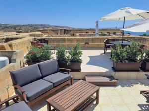 a patio with a couch and tables and an umbrella at Fort Chambray Island Views in Għajnsielem