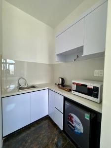 a kitchen with white cabinets and a microwave at EuroDana Palace Hotel in Danang