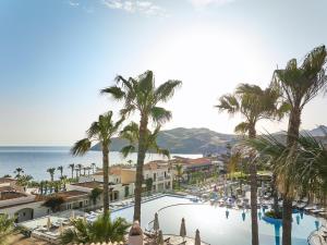a view of a resort with palm trees and the ocean at Grecotel Marine Palace & Aqua Park in Panormos Rethymno