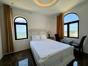 a bedroom with a white bed and two windows at EuroDana Palace Hotel in Danang
