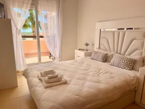 a bedroom with a large white bed with towels on it at Condado de Alhama La Isla 11SV2F in El Romero