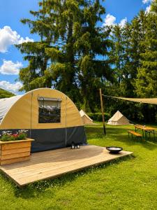 a tent sitting on a wooden deck in a field at Camping Les Pommiers in Comblain-au-Pont