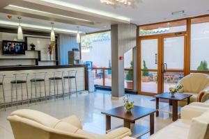 a living room with white furniture and a kitchen at Hotel Vemara Club in Byala