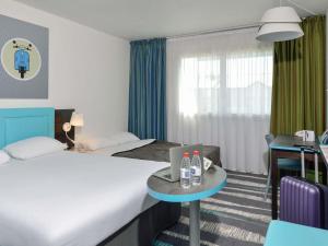 a hotel room with two beds and a table with a laptop at ibis Styles Angoulême Nord in Champniers +75 photos