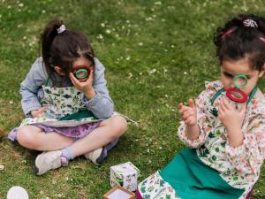 two little girls sitting on the grass with magnifying glasses at Novotel Orléans Chemins De Sologne Demeures De Campagne in Orléans